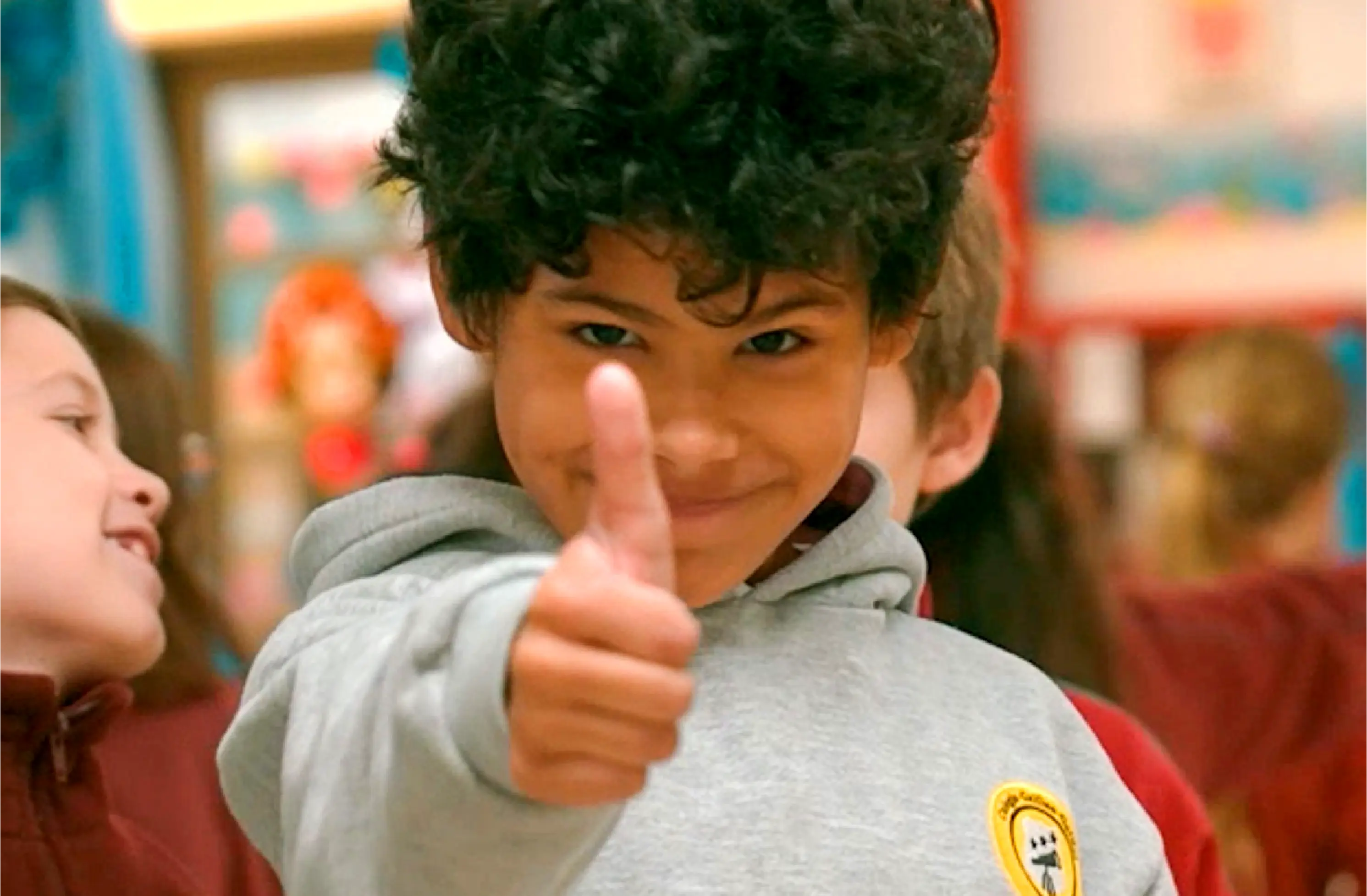 Estudiante sonriendo y levantando el pulgar durante una actividad en el colegio.
