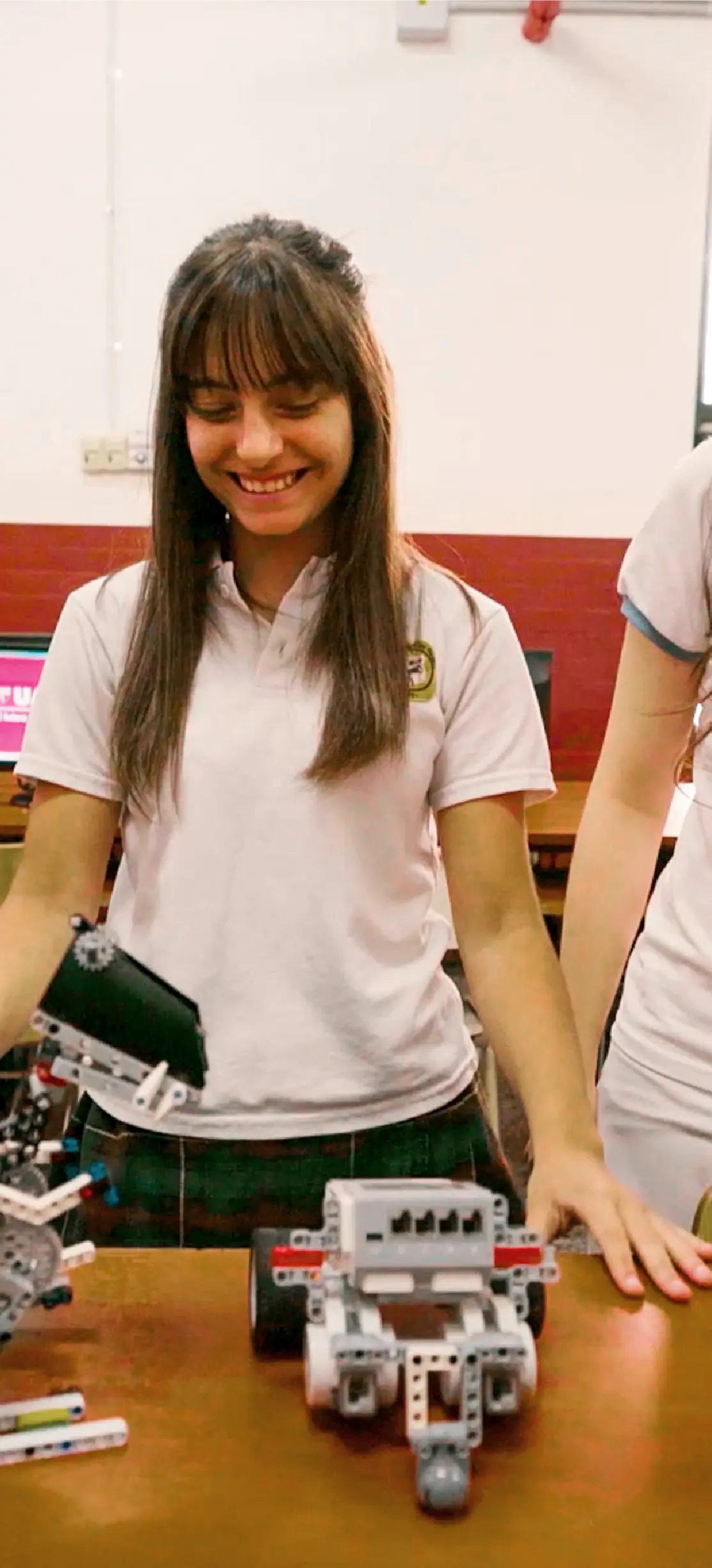 Estudiante participa en una actividad de robótica escolar con robots construidos en el aula.