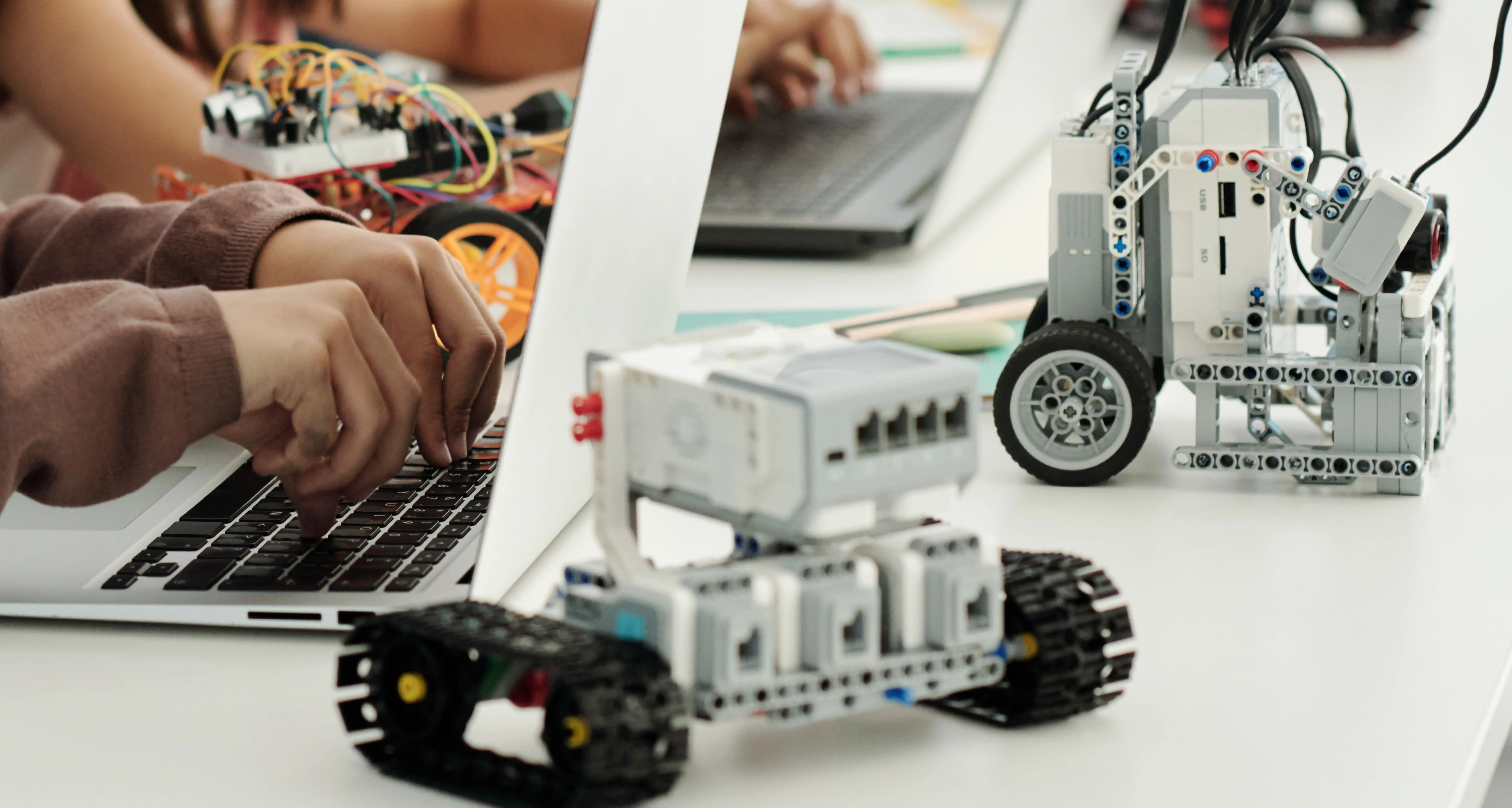 Estudiantes programan robots educativos con computadoras durante una clase de tecnología.