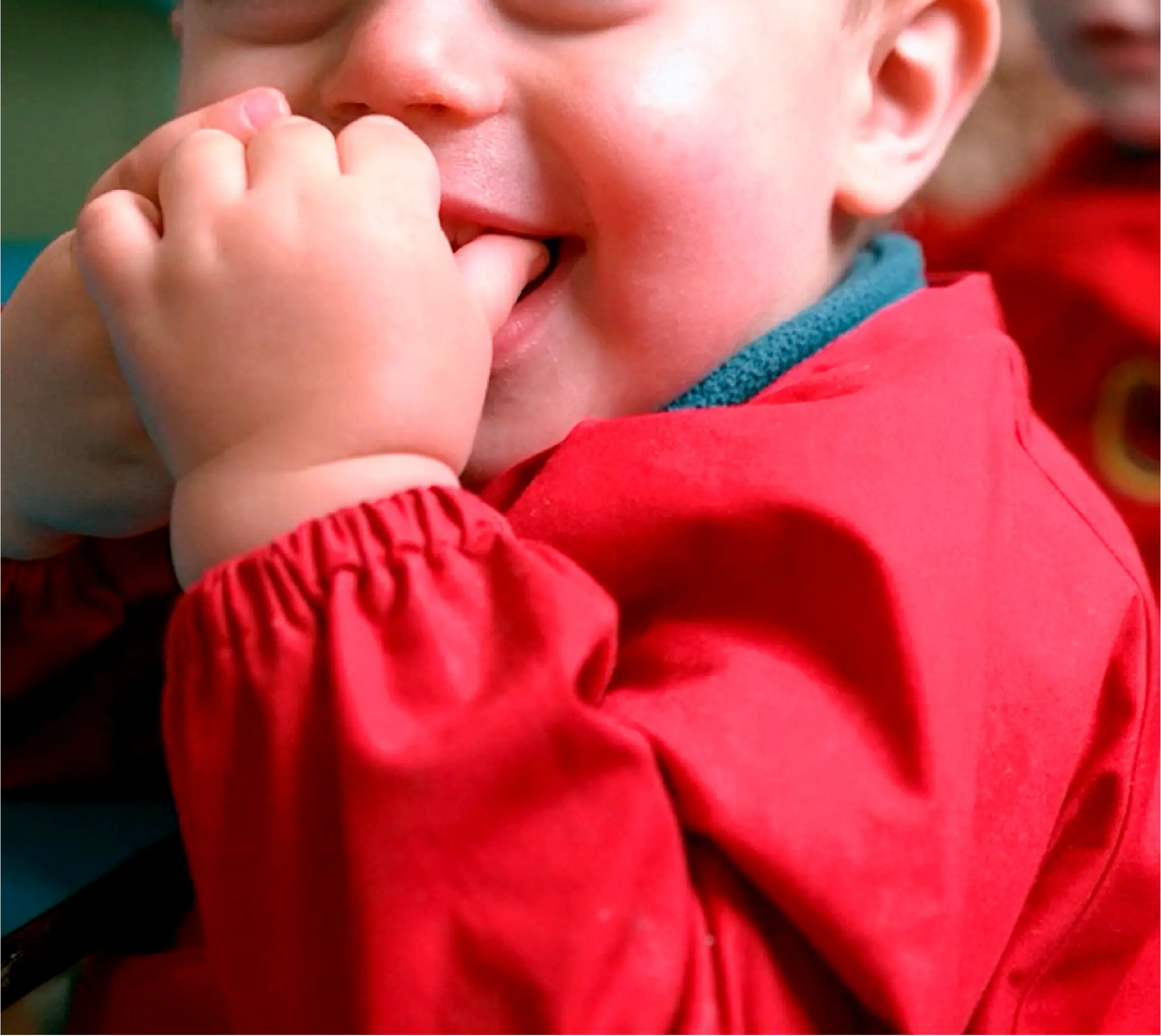 Niño pequeño sonríe durante una actividad de juego y aprendizaje en el jardín.