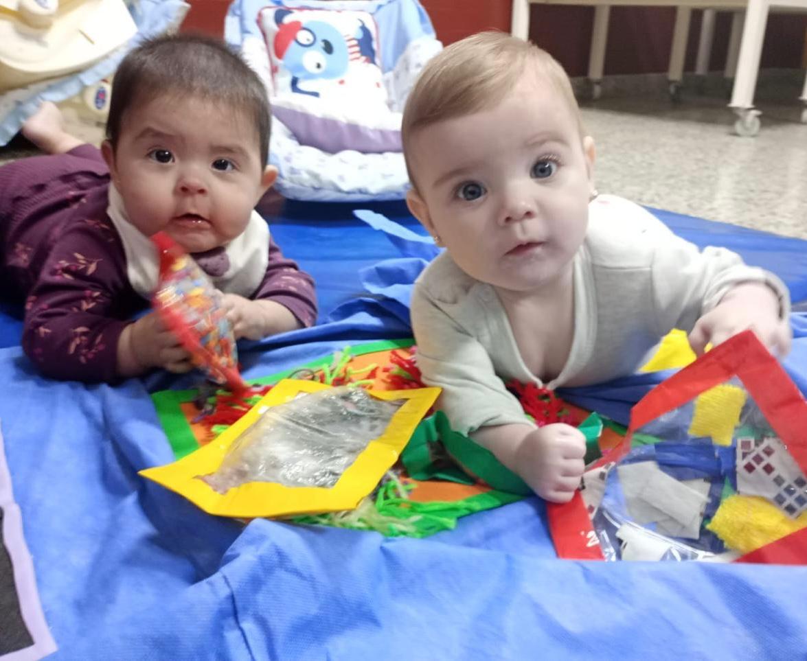 Bebés exploran materiales didácticos y sensoriales durante una actividad de nivel inicial.